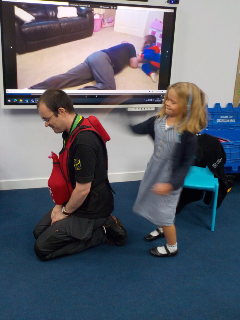Child hitting the back of man's training vest to practice how to stop someone choking.